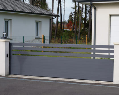 Modernes anthrazitfarbenes Schiebetor aus Polen vor einer Garage – minimalistisch und platzsparend PolenDeals.de