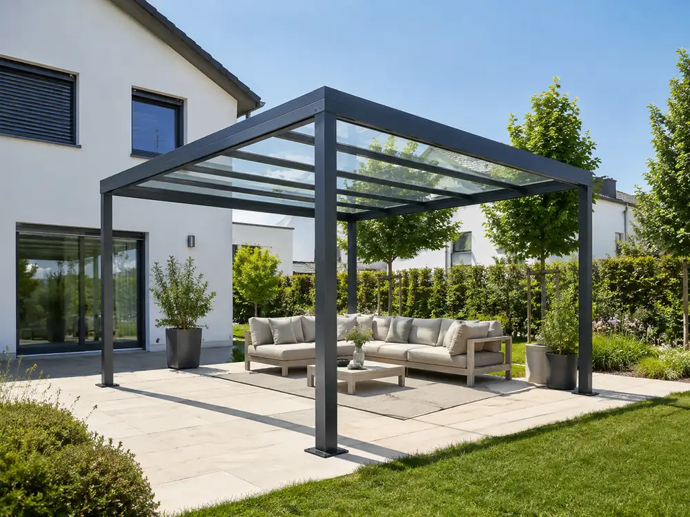 Freistehende Aluminium-Pergola mit klarem Glasdach und heller Lounge im Garten